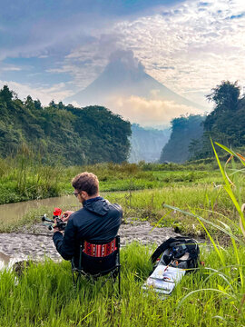 FPV pilot with drone near active volcano eruption at sunrise
