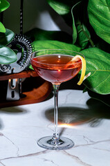 Killer Queen alcoholic cocktail drink with gin, aperitif, bitters, liqueur and lemon twist with bar...