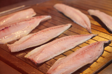 Fish fillets grilling on wooden grill during cooking time