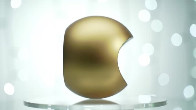 Modern golden sphere featuring a unique concave element, presented on a reflective with a bright, bokeh-filled background.