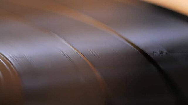 Abstract close-up captures the textured of a dark, grooved object, highlighting its reflective lines and unique patterns.