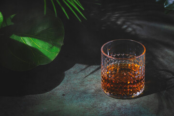 Smoky whiskey, bourbon or scotch in glass. Dusk green background, elegant night decoration
