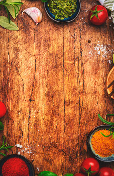 Healthy cooking and food background with spices, herbs, curry and kitchen utensils on wooden cutting board, top view. Peppercorn, garlic, basil, lemon, tomatoes and other ingredients