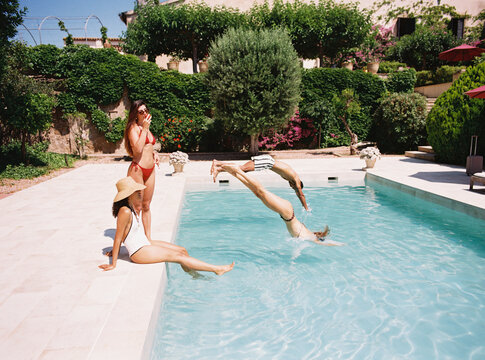 Friends diving and relaxing in swimming pool at luxury hotel