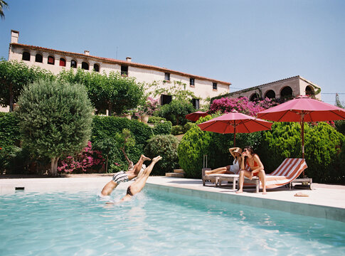 Friends diving into swimming pool at luxury hotel resort