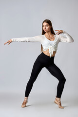 A woman in a white shirt and black pants is dancing