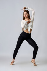 A woman in a white shirt and black pants is posing for a picture