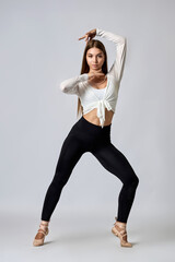 A woman in a white shirt and black pants is posing for a picture