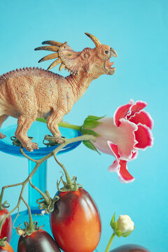 Colorful dinosaur toy standing on vegetables with flowers