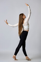 A woman in a white shirt and black pants is dancing