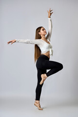 A woman in a white shirt and black pants is dancing