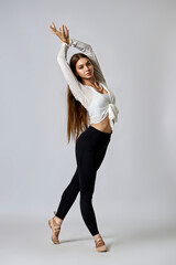 A woman in a white shirt and black pants is posing for a picture