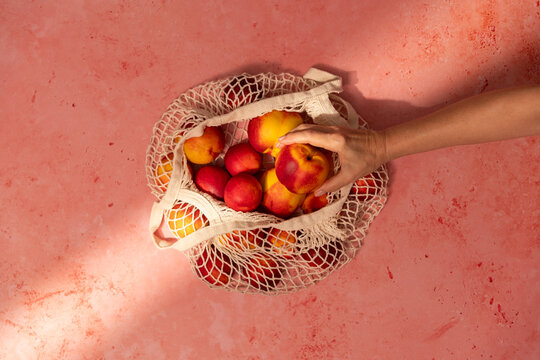Fresh peaches in a Natural Bag on Pink table