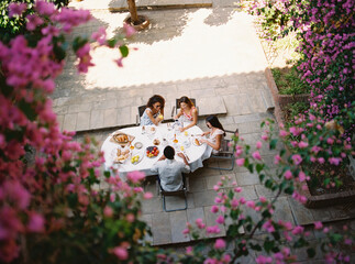 Friends enjoying breakfast in beautiful blooming courtyard