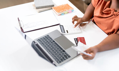 Close-up of woman using calculator, laptop, and credit cards for financial planning.