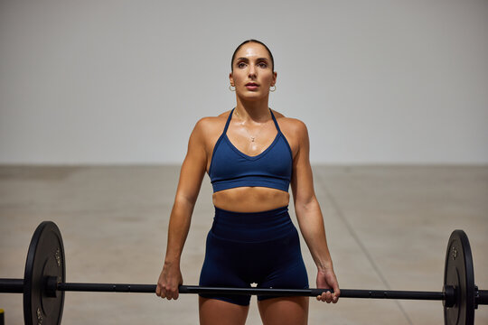 Strong woman lifting barbell in gym during workout session
