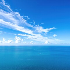 Fototapeta premium A breathtaking aerial view of the vast ocean, showcasing vibrant blue waters, gentle waves, and scattered white clouds reflecting sunlight.
