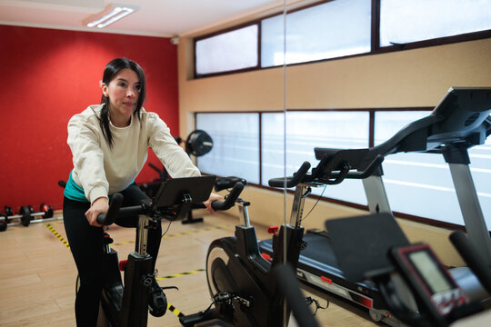 Woman Warming Up on Stationary Bike in Apartment Gym