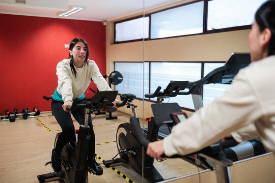 Young Woman on Indoor Cycling in Apartment Gym
