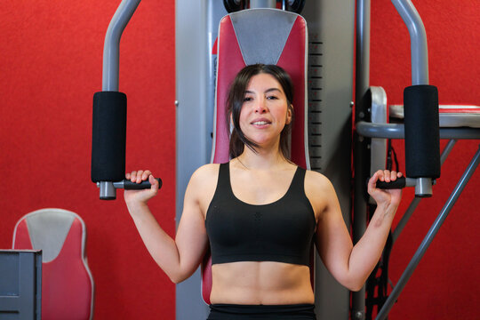 Latina Woman Using Chest Press Machine in Home Gym
