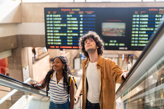 Young tourists going up the escalator at the station are looking