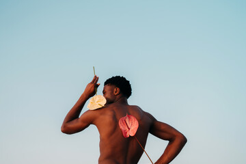 Copyspace portrait of Black Man With Flowers Against Blue Sky