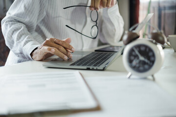 asian businessman using laptop working on table before work time end in a day,  time management...