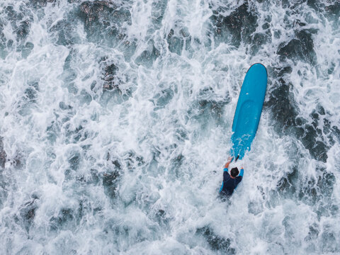 Aerial view of a surfer on a blue board in waves