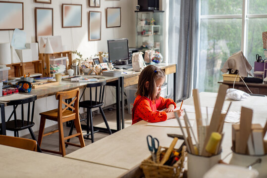 Child drawing with pencils at the table in the art studio