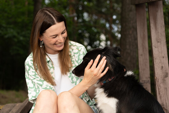 Woman Smiling and Petting Border Collie Dog

