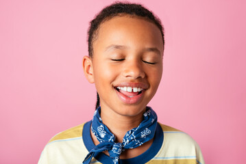 Joyful Child with Eyes Closed Against Pink Background in studio