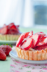 Close-up of Strawberry Tart with Spoon. A close-up, detailed shot of a strawberry tart on a white plate with a decorative spoon.