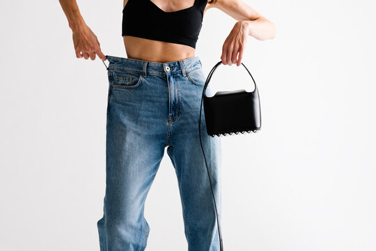 Person Displaying Baggy Jeans and Fashionable Black Handbag With