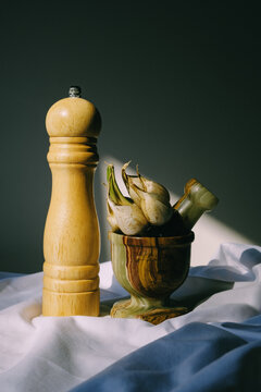 Wooden pepper mill and mortar with garlic on white fabric