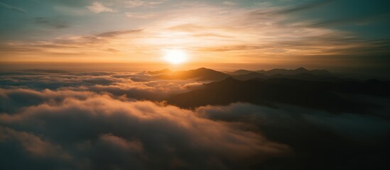 A breathtaking sunrise illuminates misty mountains, casting golden hues over a sea of clouds, creating a serene and tranquil landscape.