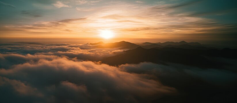 A breathtaking sunrise illuminates misty mountains, casting golden hues over a sea of clouds, creating a serene and tranquil landscape.