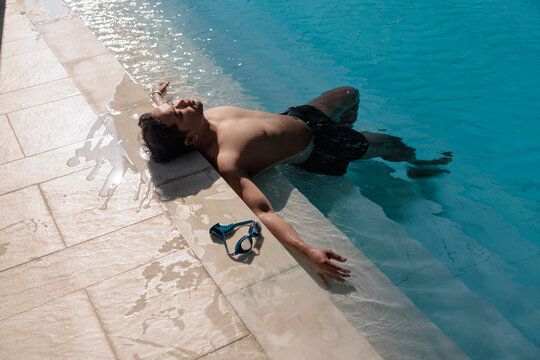 Man relaxes in pool with goggles on the side.