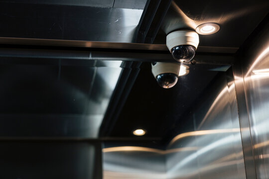 Security camera and light fixture in a metal elevator.