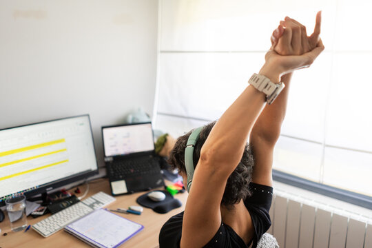 Woman stretching arms at home office desk after working on computer