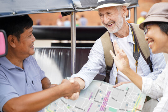 American senior couple tourist are congratulatory handshake with the Tuktuk Thailand taxi driver after ask for them destination on the map . Senior tourist concept - Powered by Adobe