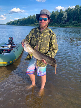 Fisherman holding large pike in river