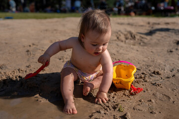 joyful toddler plays with sand and water using red shovel and yellow bucket on sunny beach, capturing innocence and adventure in warm afternoon light, closetovature, community, dirt, imagination