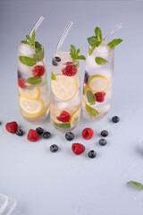 refreshing lemons, raspberries, and blueberries infused in tall ice-filled glasses with mint against a light backdrop, presentation, garnish, bright, aesthetic, minimalist, photography, still, decor