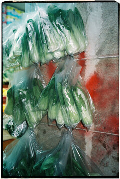 bok choy bundles hanging outside shop, 35mm