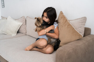 Child Hugs Small Dog While Sitting on Sofa in Cozy Living Room