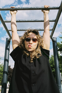 Woman hanging from a playground structure on a sunny day