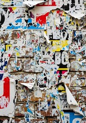 Fototapeta premium Textured background of torn posters on a brick wall, urban decay and grunge aesthetic