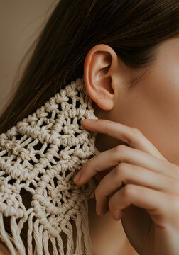 Woman wearing intricate macrame earrings gently touches her earlobe while showcasing the detailed craftsmanship of the handmade design.