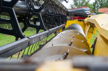 Close-up of agricultural machinery with metal blades and green field background