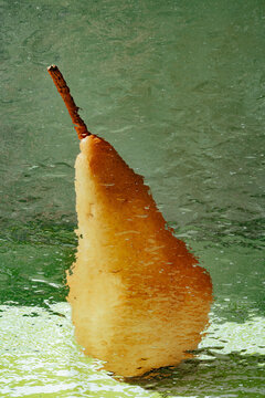 Pear resting on a slick surface behind frosted glass